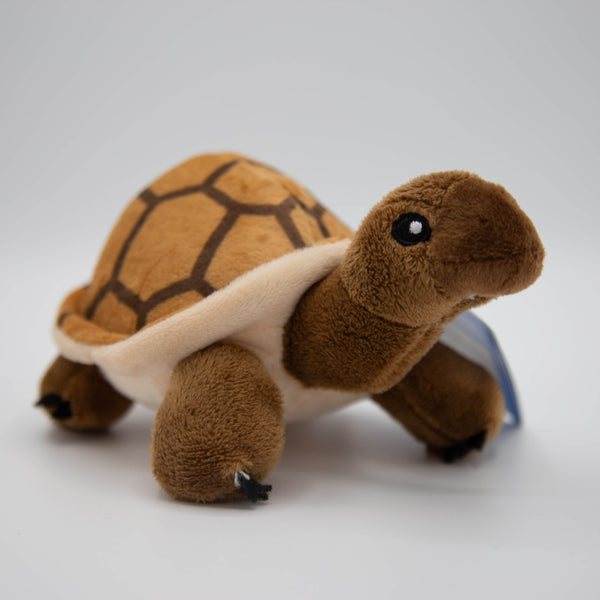 A brown small tortoise toy, with a tanned shell, cream underbelly and brown head, neck and legs