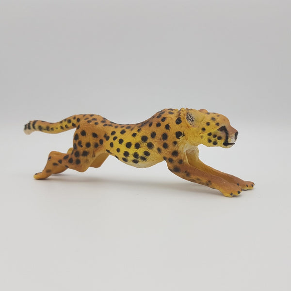 Side view of a yellow plastic running cheetah toy with black spots.